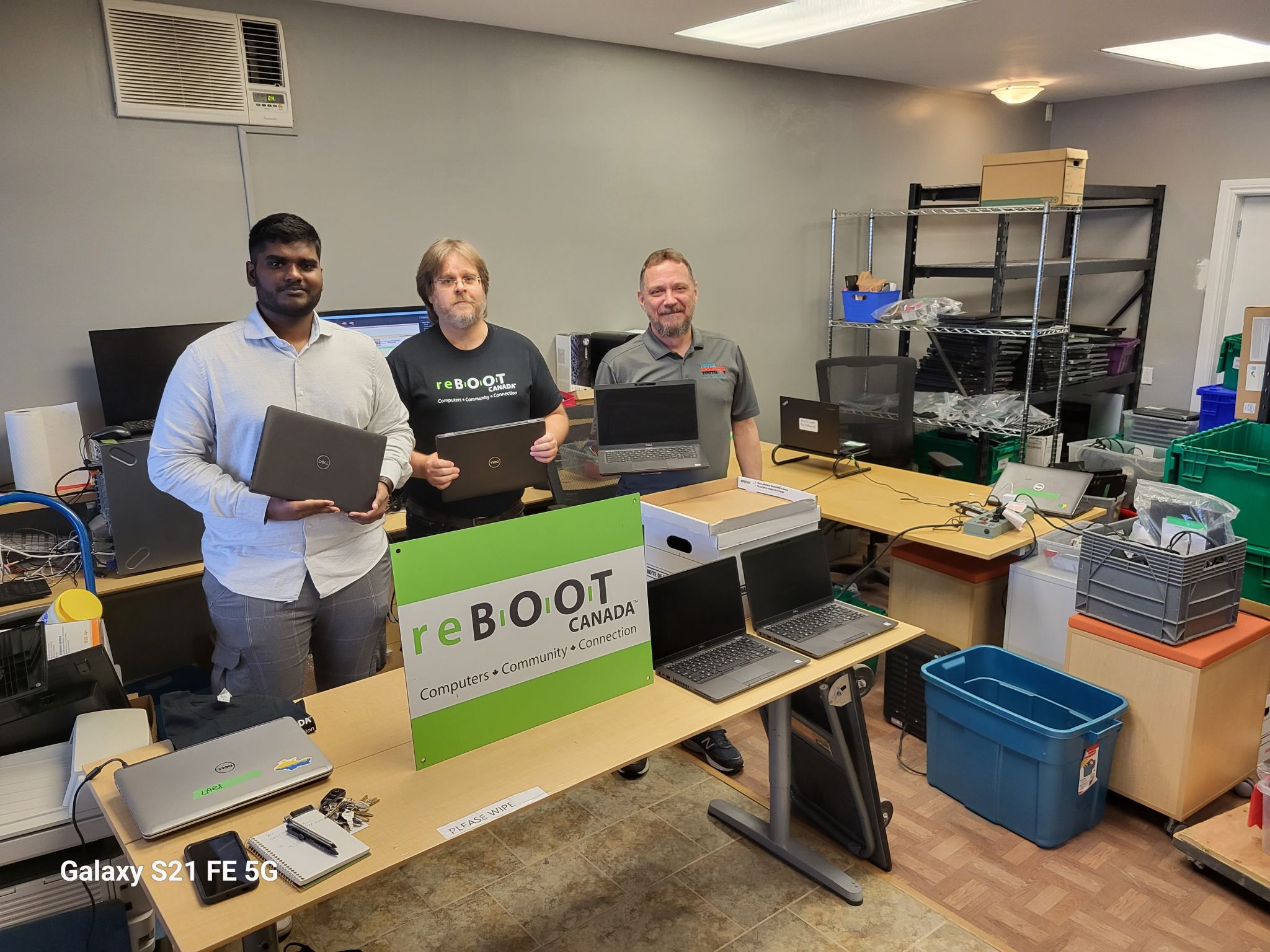 Representatives of reBOOT Canada and Avanade present laptops to a representative of Youth Assisting Youth.