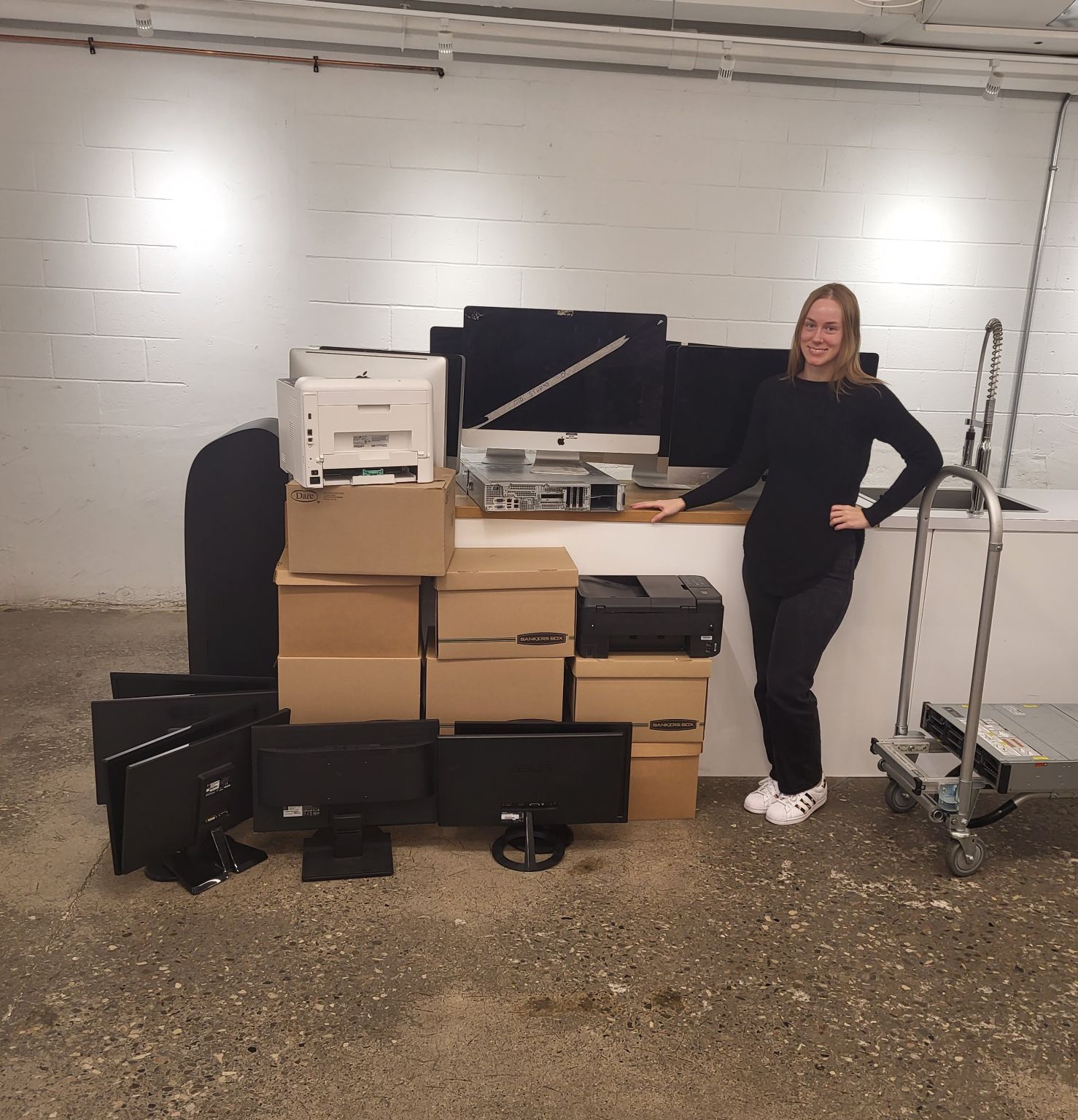 A representative of TAG Marketing poses with a large donation of retired IT equipment.
